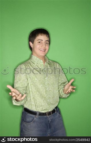 Portrait of Caucasian teen boy with hands opened towards viewer standing against green background.