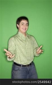 Portrait of Caucasian teen boy with hands opened towards viewer standing against green background.