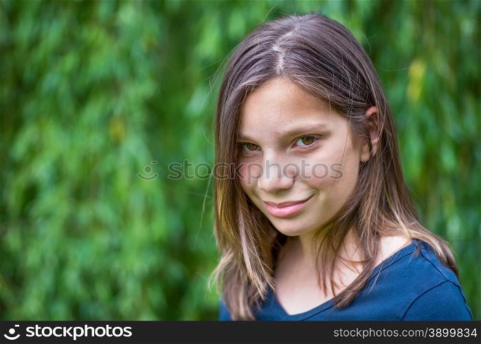 Portrait of caucasian teenage girl in front of green willow