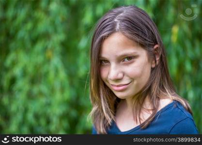 Portrait of caucasian teenage girl in front of green willow