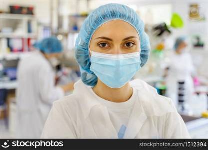 Portrait of caucasian woman wearing protective mask and bouffant mob cap - Young female doctor or scientist at the laboratory or hospital front view in day - protection and solution concept