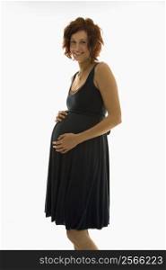 Portrait of Caucasion mid-adult attractive pregnant woman standing with hands on belly, looking at viewer and smiling.