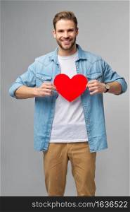 Portrait of charming man hold hand paper heart shaped card wear casual style shirt isolated over grey background.. Portrait of charming man hold hand paper heart shaped card wear casual style shirt isolated over grey background