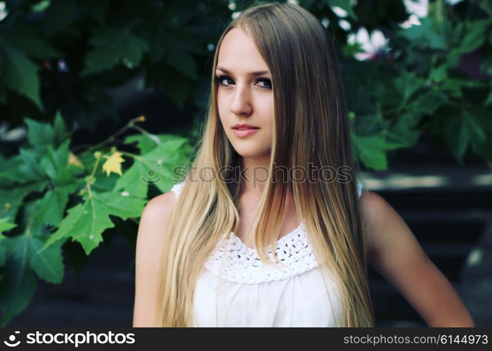 Portrait of charming young girl with long hair. Attractive young woman walking in a park on a sunny day.