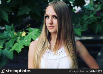 Portrait of charming young girl with long hair. Attractive young woman walking in a park on a sunny day.