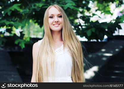 Portrait of charming young girl with long hair. Attractive young woman walking in a park on a sunny day.