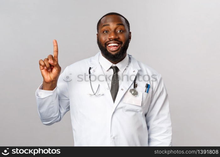 Portrait of cheerful african-american male doctor explain one simple task for patient stay healthy, not getting covid19, make daily check-up in hospical, smiling and showing number one, index finger.. Portrait of cheerful african-american male doctor explain one simple task for patient stay healthy, not getting covid19, make daily check-up in hospical, smiling and showing number one, index finger