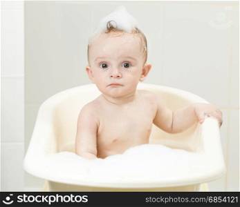 Portrait of cheerful baby boy sitting in bath