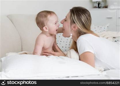 Portrait of cheerful baby with mother lying on big white pillow