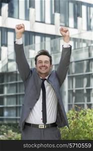 Portrait of cheerful businessman celebrating success outside office building