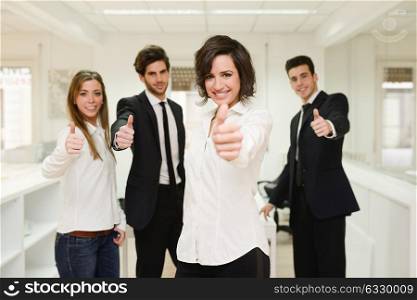 Portrait of cheerful businessteam giving thumbs up with a young woman as leader