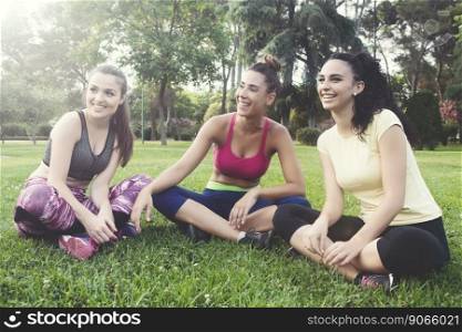 Portrait of cheerful candid athletes laughing while sitting on grass