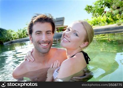 Portrait of cheerful couple bathing in natural pool