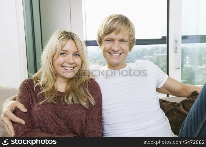 Portrait of cheerful couple sitting on sofa at home
