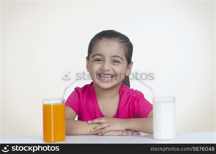 Portrait of cheerful girl with orange juice and milk against colored background
