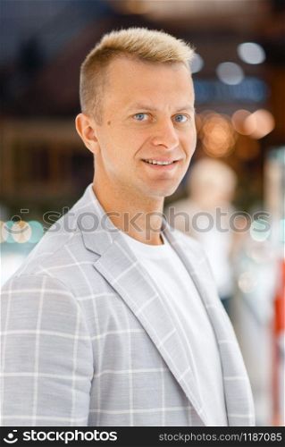 Portrait of cheerful man in light suit with large white cells, blur background. Executive male person, successful businessman, confident business person