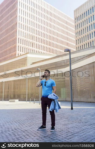 Portrait of cheerful modern businessman speaking by phone and smiling while standing outdoors