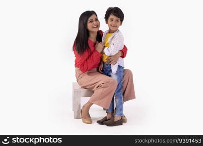 Portrait of cheerful mother and son looking away against white background