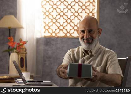 Portrait of cheerful senior man holding gift box