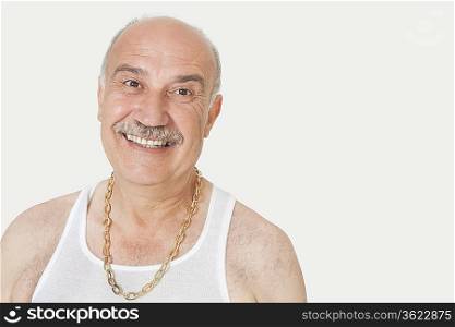 Portrait of cheerful senior man in vest over gray background