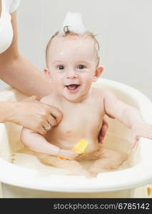 Portrait of cheerful smiling baby boy having bath with foam