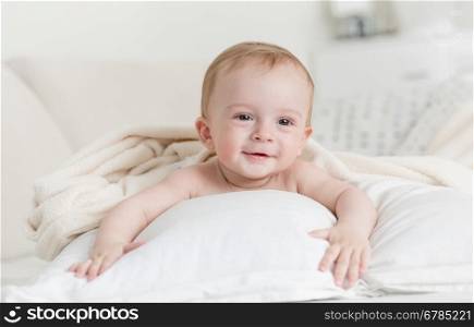 Portrait of cheerful smiling baby boy lying on big bed