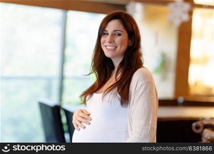 Portrait of cheerful smiling pregnant girl at home, having a good time, enjoying pregnancy, happy family life
