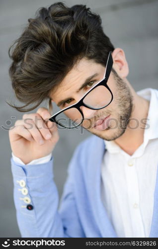 Portrait of cheerful trendy guy with black eyeglasses on