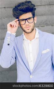 Portrait of cheerful trendy guy with black eyeglasses on wearing blue blazer jacket