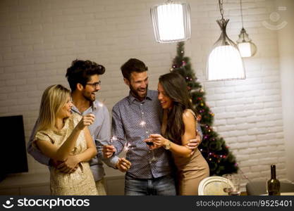 Portrait of cheerful women and men celebrating New Year eve with sparkles and wine at home