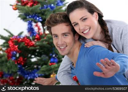 portrait of cheerful young couple posing near Christmas tree