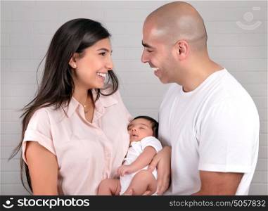 Portrait of cheerful young parents holding on hands cute newborn daughter, healthy childhood, happy parenthood concept