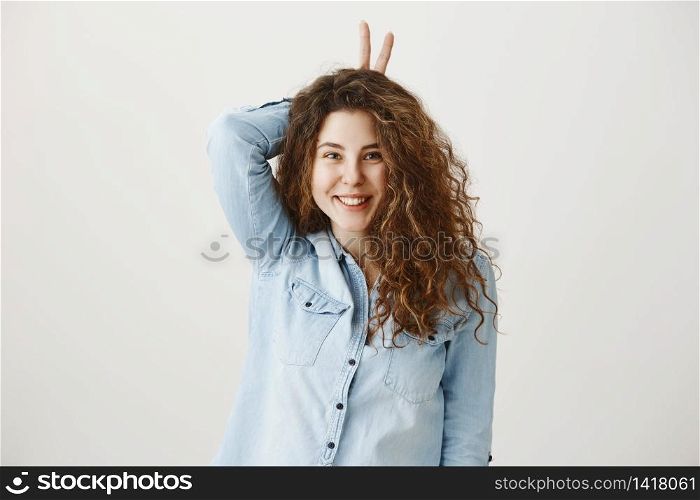 Portrait of cheerful young woman showing two fingers or victory gesture, over grey background. Portrait of cheerful young woman showing two fingers or victory gesture, over grey background.
