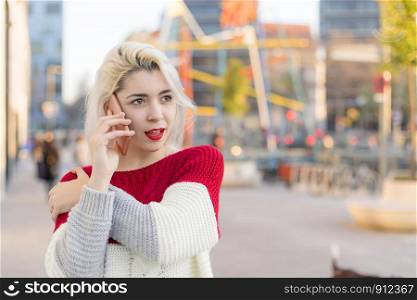 Portrait of cheerful young woman talking on smartphone outdoors.