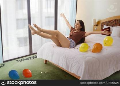 Portrait of cheerful young woman with colourful balloons enjoying on bed