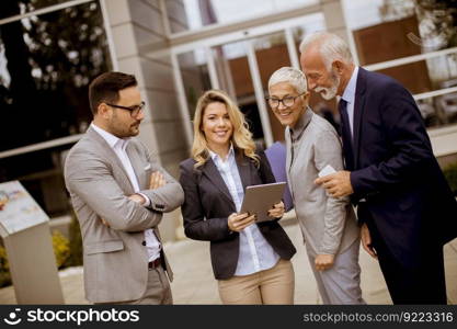 Portrait of cheerfull senior and young business people standing in front of building office