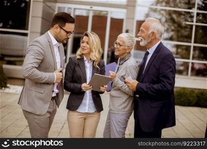 Portrait of cheerfull senior and young business people standing in front of building office