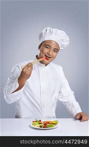 Portrait of chef eating capsicum with chopsticks