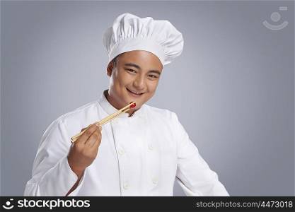 Portrait of chef eating cherry tomato with chopsticks