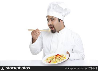 Portrait of chef eating pasta with chopsticks