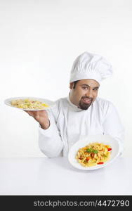 Portrait of chef holding plates with pasta
