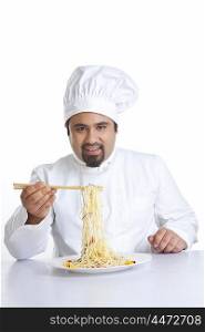 Portrait of chef lifting pasta with chopsticks