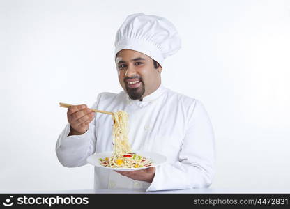 Portrait of chef lifting pasta with chopsticks