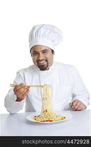 Portrait of chef lifting pasta with chopsticks