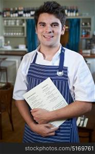 Portrait Of Chef Standing In Restaurant Holding Menu
