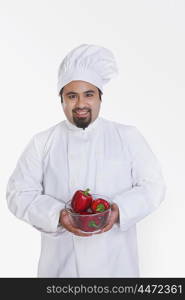 Portrait of chef with bowl of red capsicum