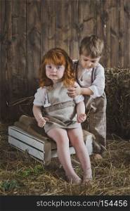 Portrait of children playing in the barn.. Children are sitting on the white boxes among the hay 6081.
