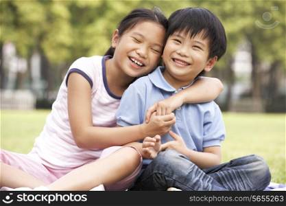Portrait Of Chinese Boy And Girl Sitting In Park Together