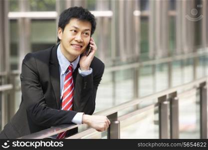 Portrait Of Chinese Businessman Outside Office On Mobile Phone