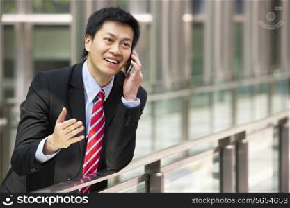 Portrait Of Chinese Businessman Outside Office On Mobile Phone